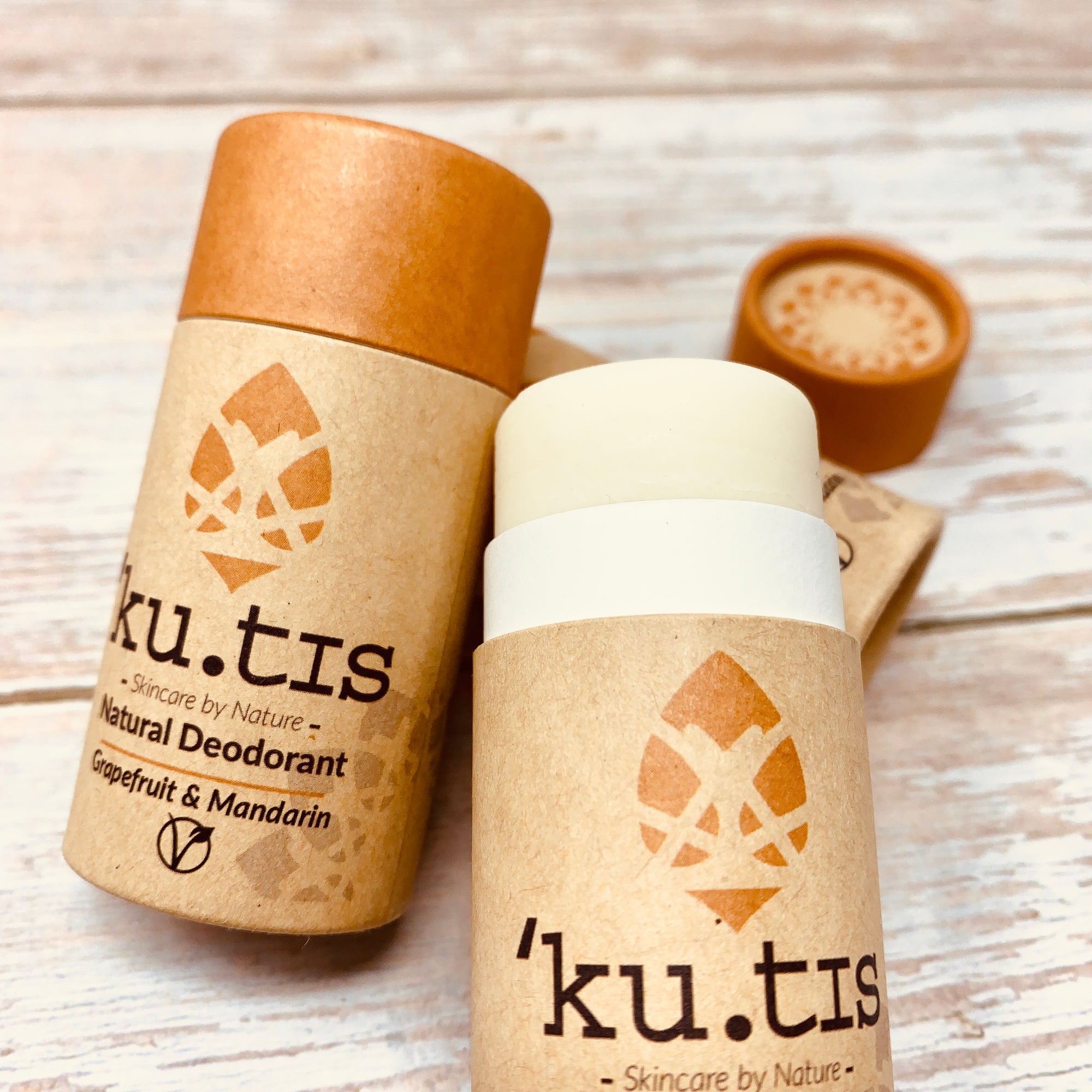 kutis vegan deodorant in a cardboard tube with orange cap, one deodorant is open to show the inside white stick